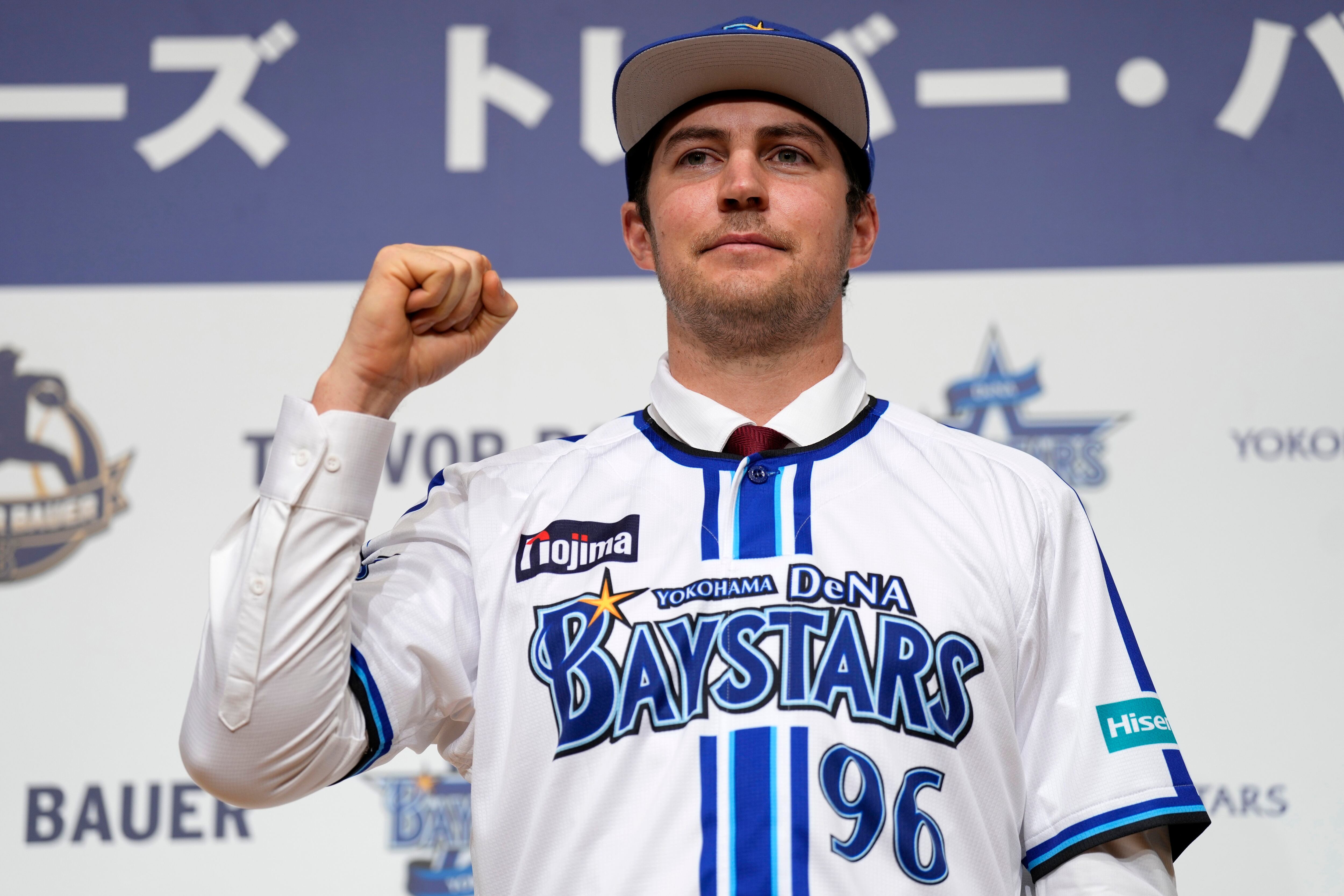 Trevor Bauer with his new uniform and cap of Yokohama DeNA BayStars poses  for photographers during a photo session of the news conference Friday,  March 24, 2023, in Yokohama, near Tokyo. (AP